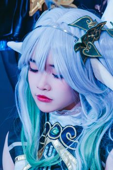 Close-up of a woman in intricate fantasy cosplay with colorful wig and costume details.