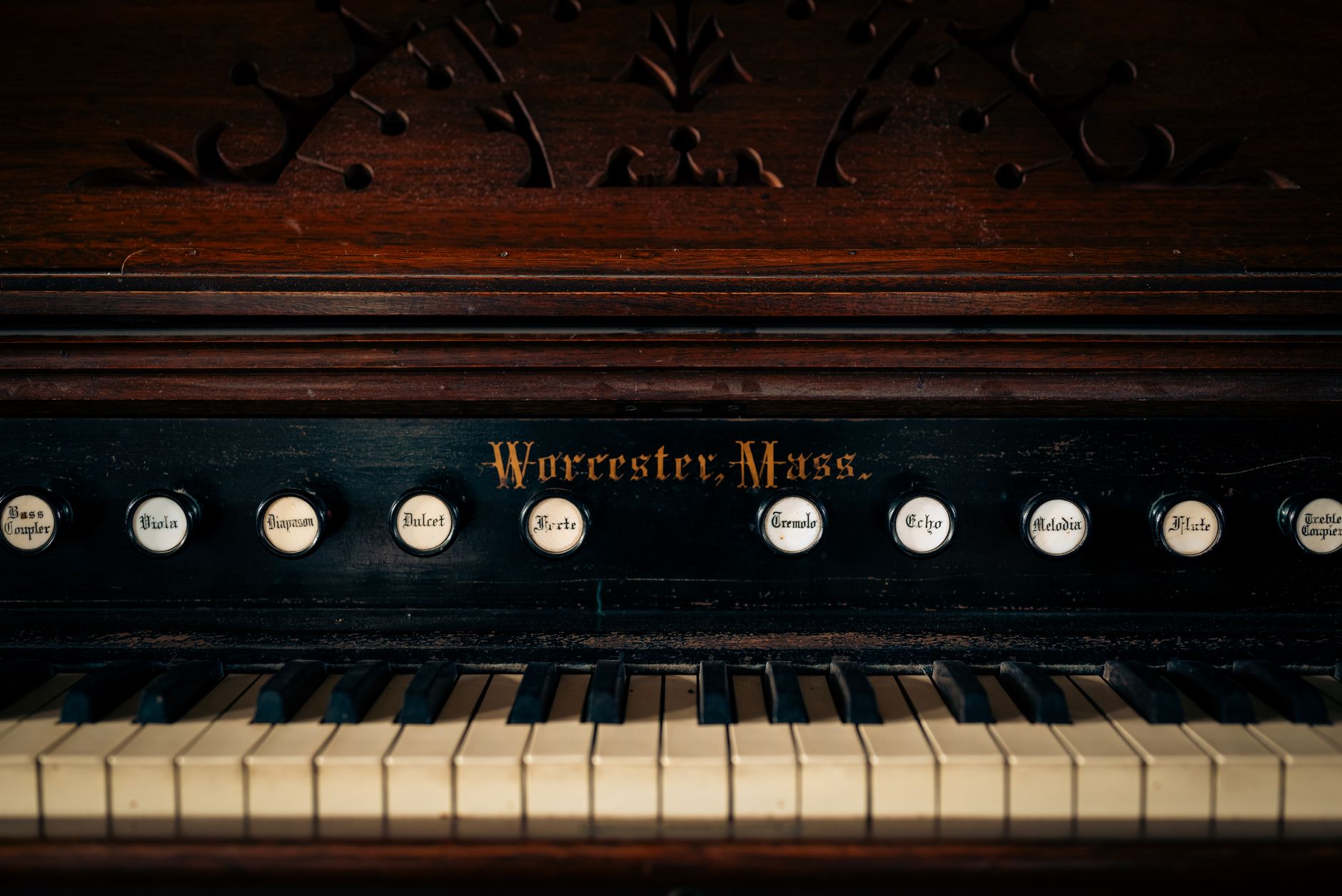Close-up of a vintage piano with organ buttons, showcasing intricate design and history.