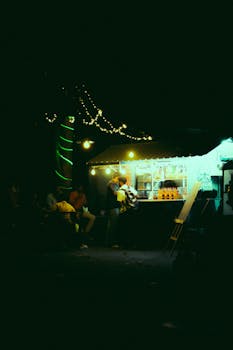 Illuminated street food stand at night with people enjoying evening snacks and atmosphere.