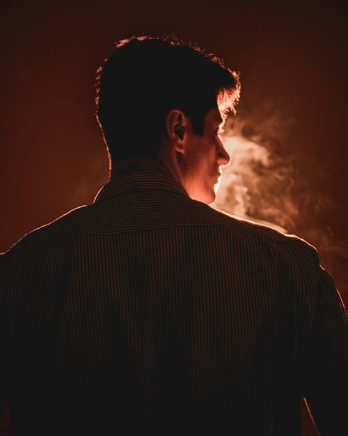 Free Silhouette of a man in a striped shirt with smoke, back view. Stock Photo