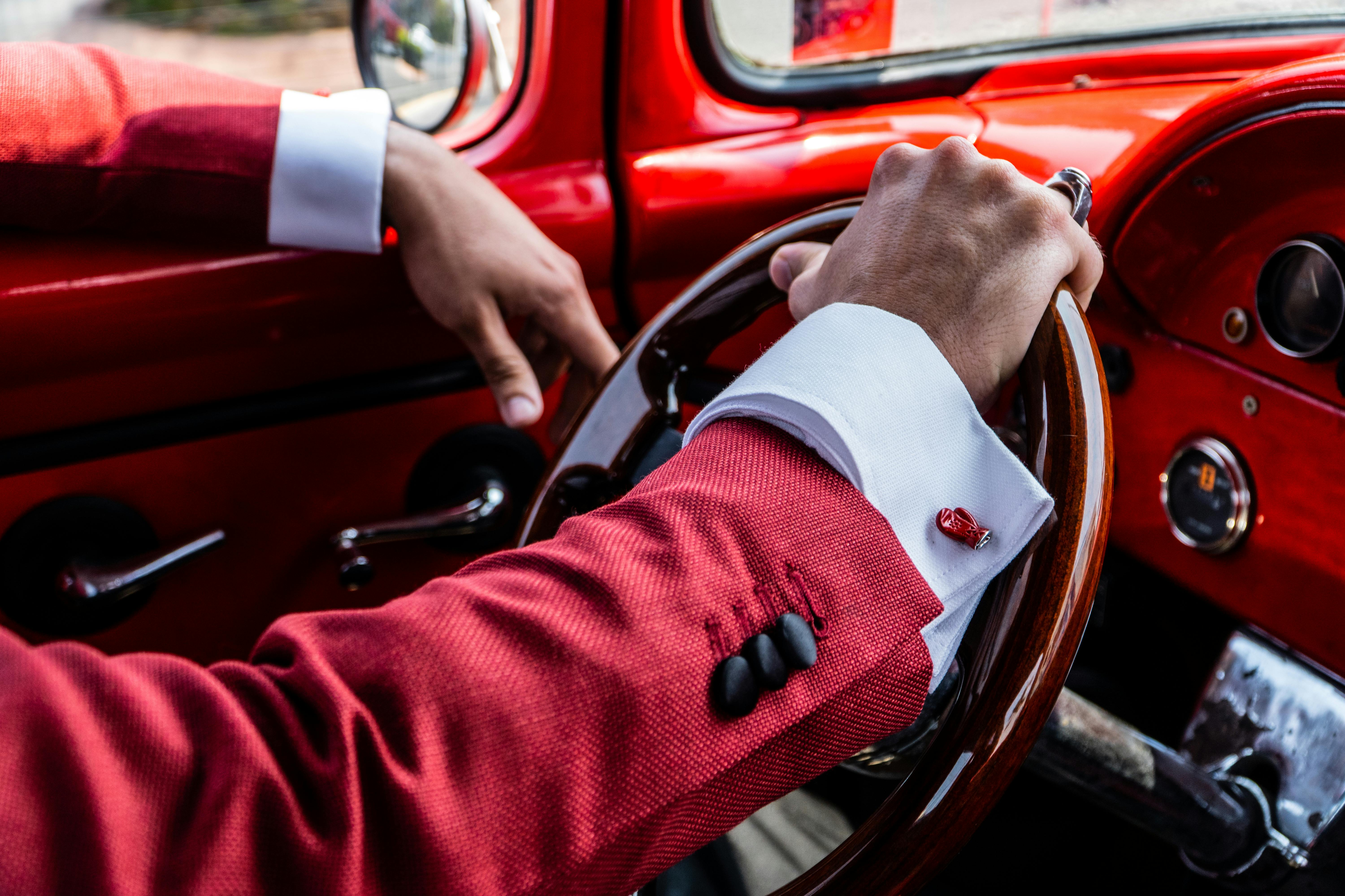 man in a suit driving a vintage car