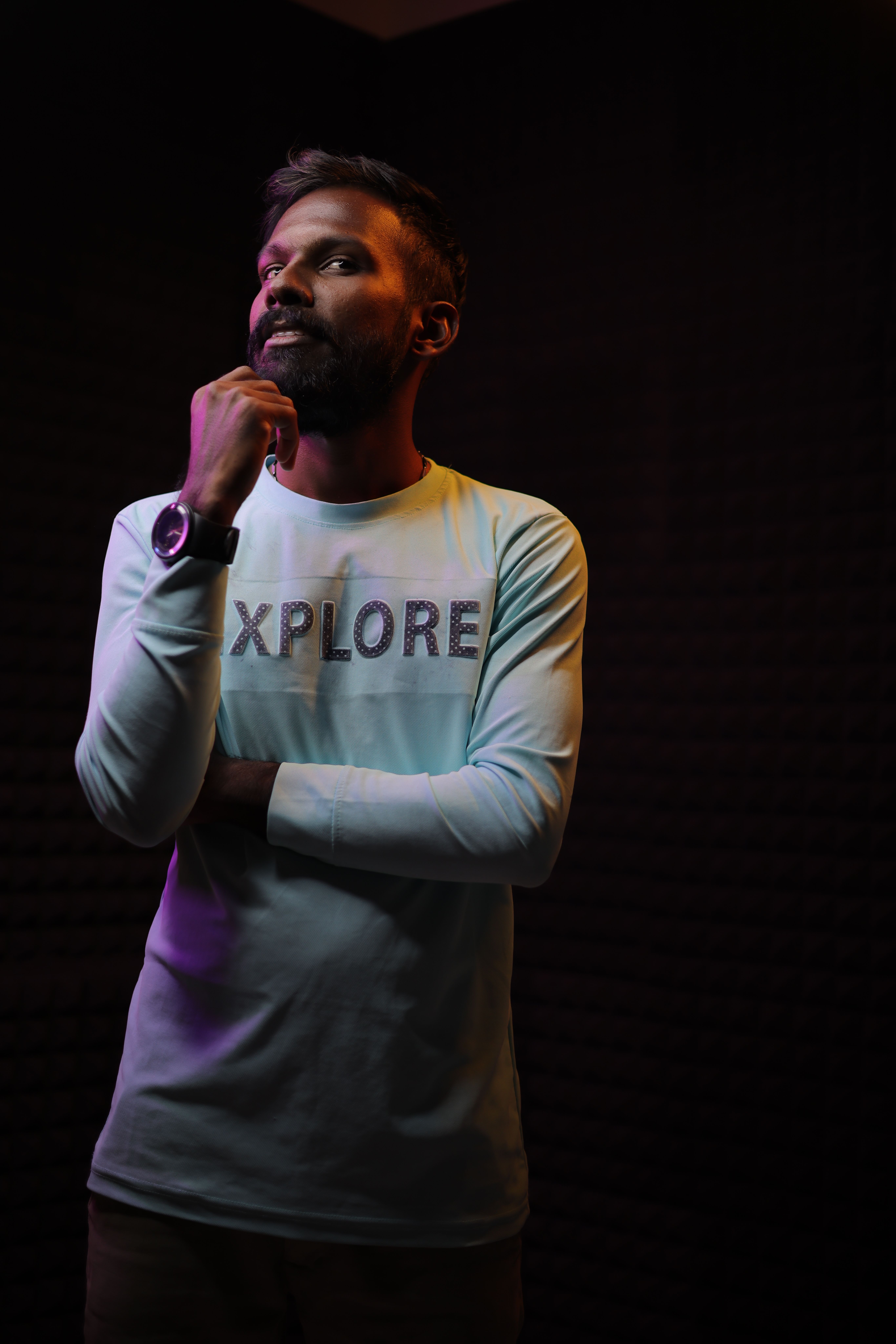 Contemplative man in a studio setting, wearing white clothing and looking upwards. Captures a thoughtful moment.