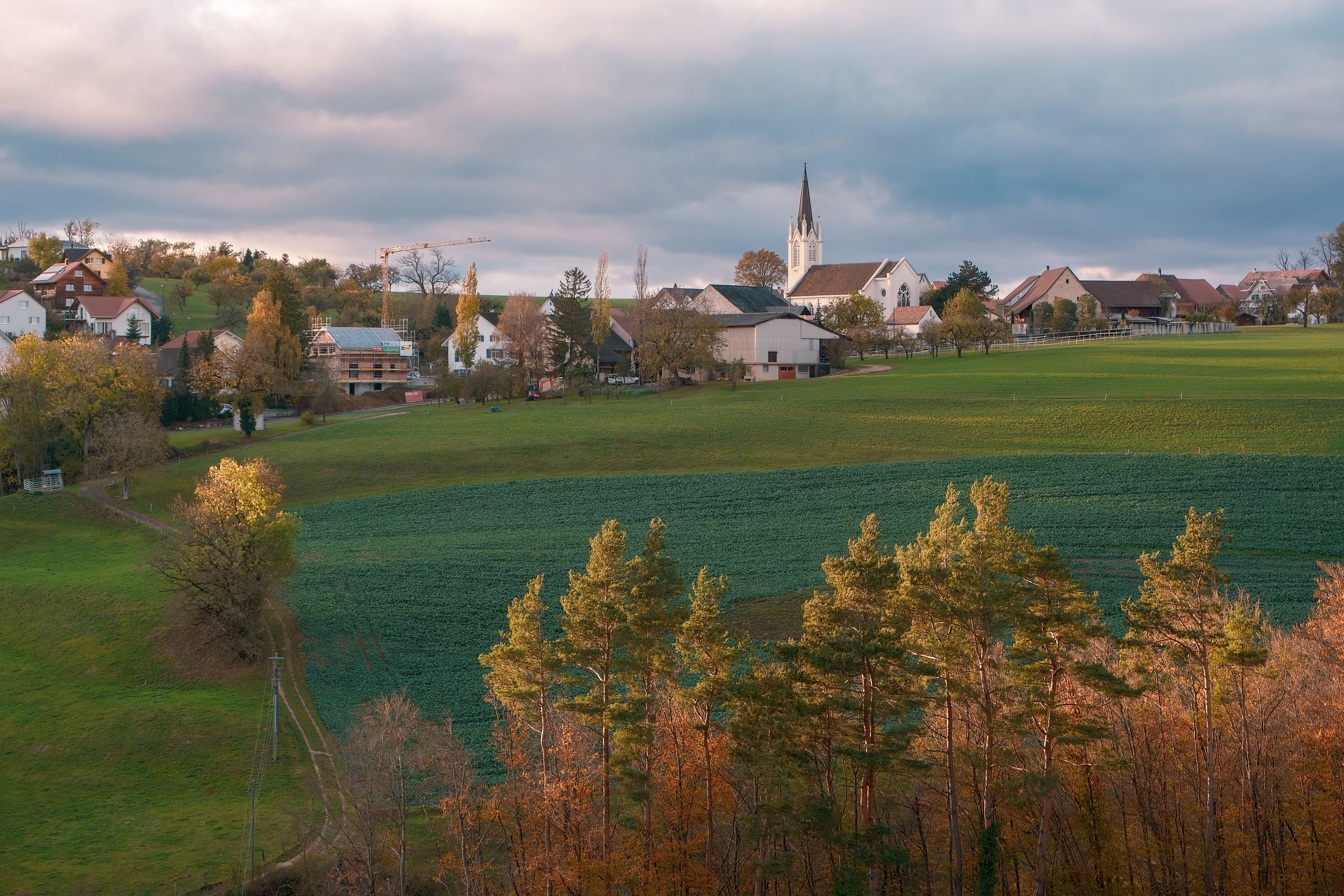 Picturesque village with church and fields during autumn, featuring vibrant colors and serene vibes.