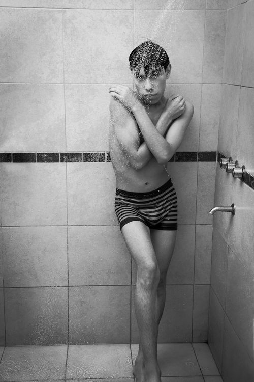 Free Artistic black and white photo of a shirtless man taking a shower, showcasing monochrome tones. Stock Photo