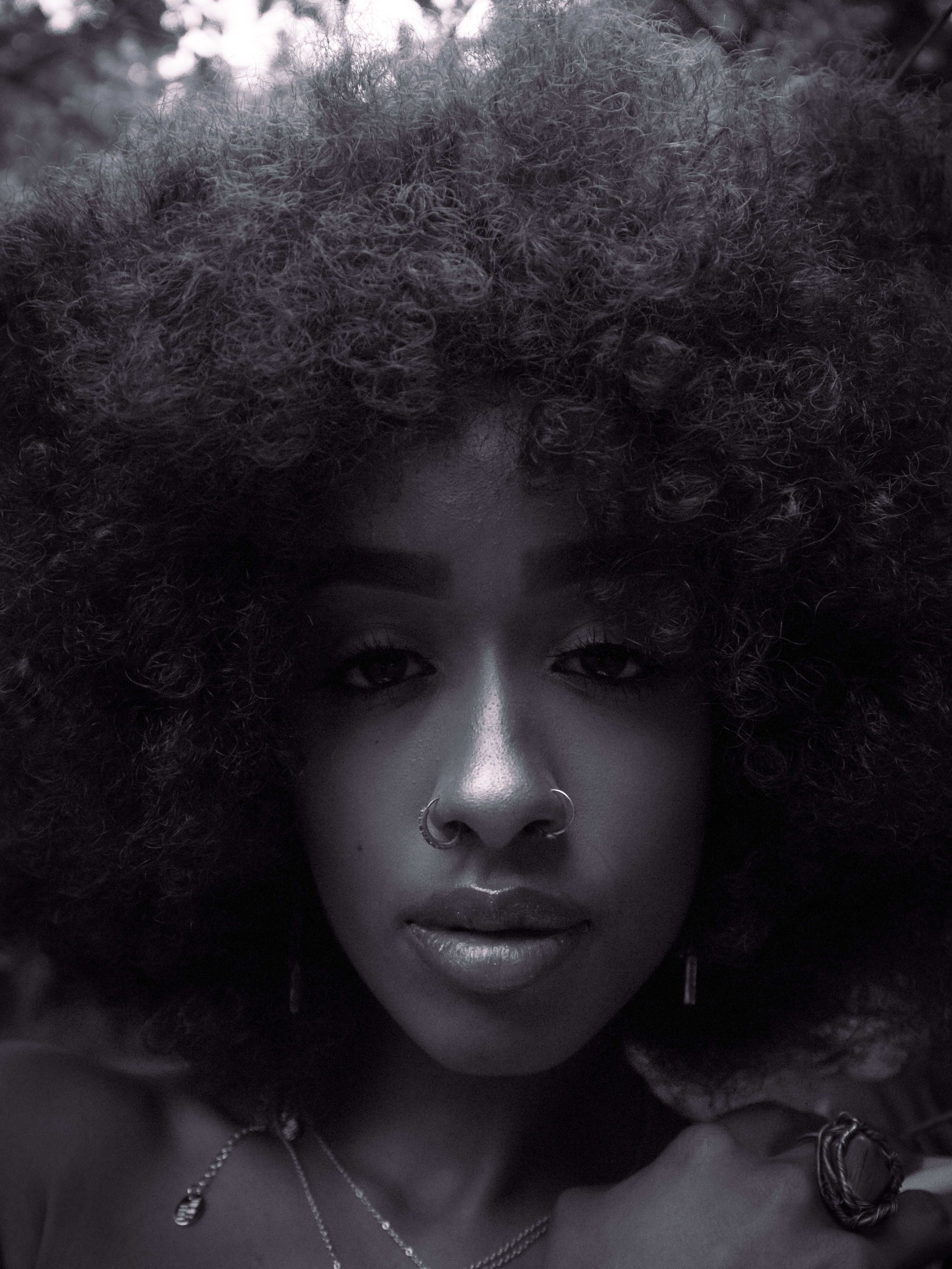 Black and white close-up portrait of a woman with an Afro hairstyle expressing elegance and confidence.