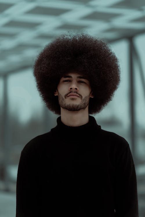 Young Man with Curly Hair Posing in Black Turtleneck Sweater