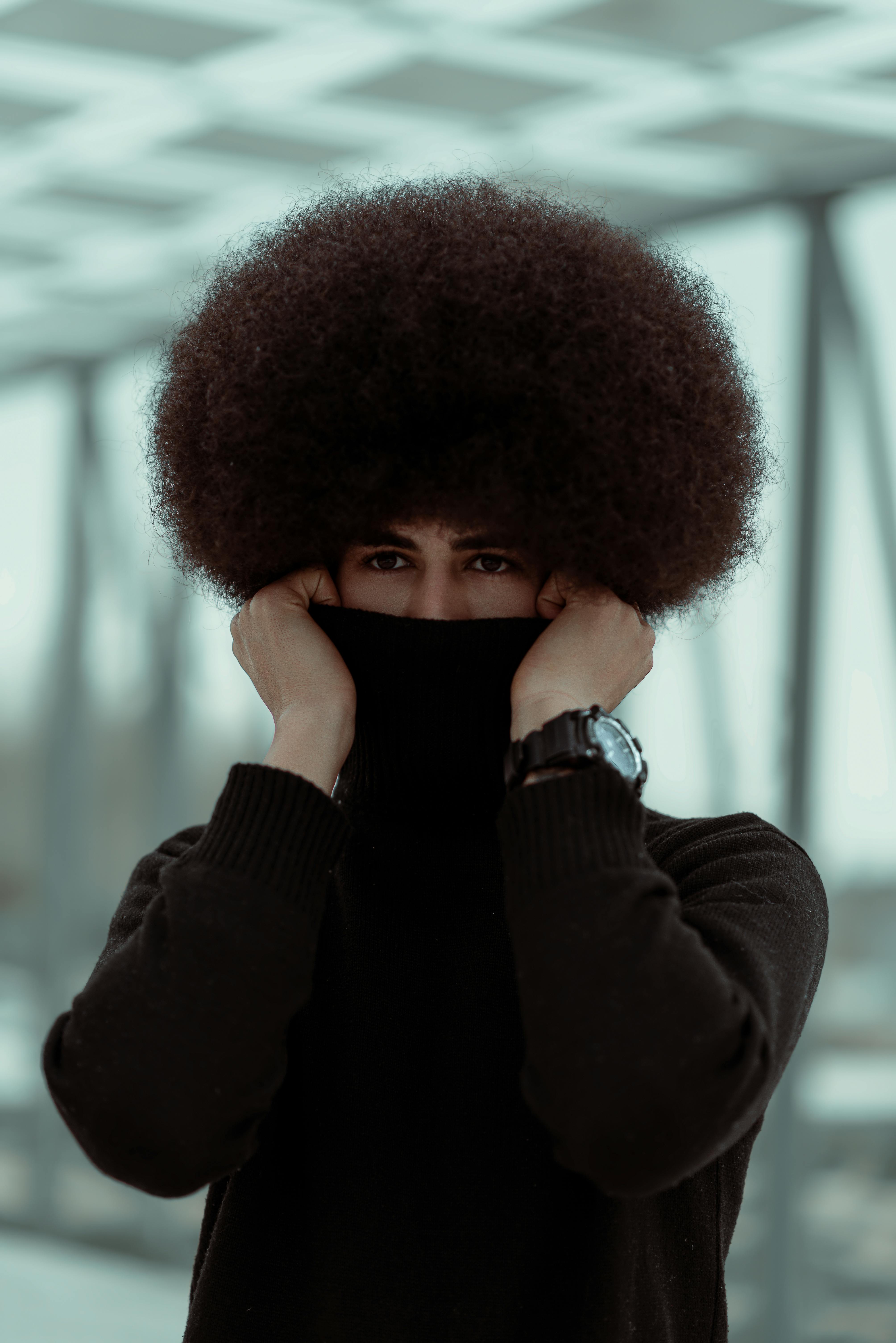 man with curly hair posing in turtleneck sweater