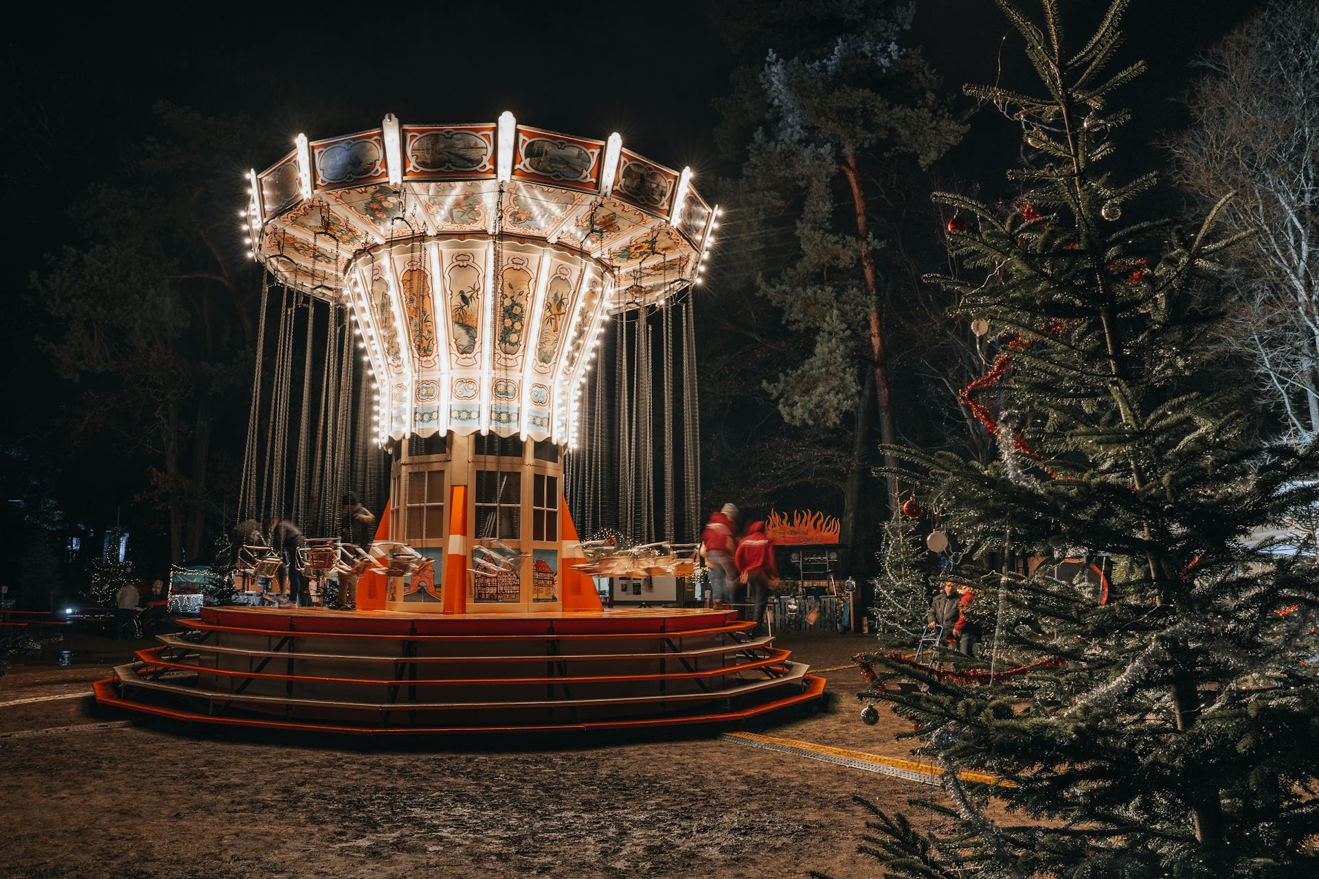 Beautifully lit carousel at night in an enchanting winter-themed amusement park setting.