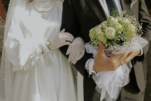 Newlyweds Walk Hand in Hand Carrying Flowers