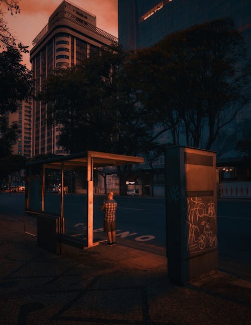 Man Standing by Bus Stop in City at Dawn