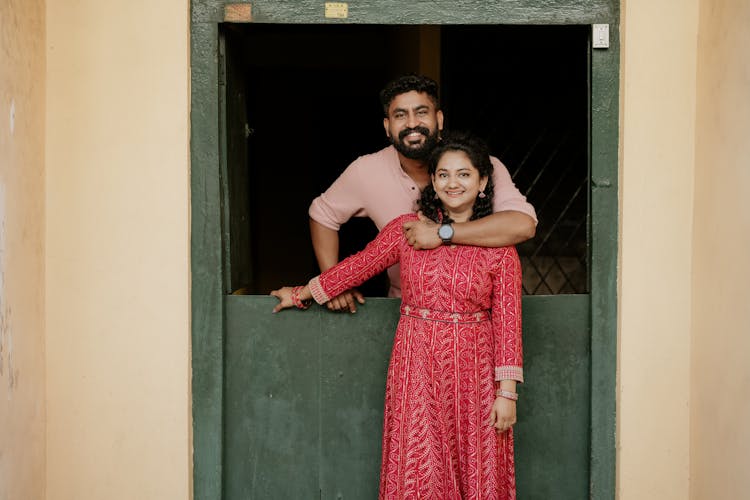 Man Standing In Window Hugging Woman From Behind