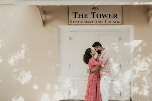 Engaged Couple Embracing in Front of the Door of a Closed Restaurant