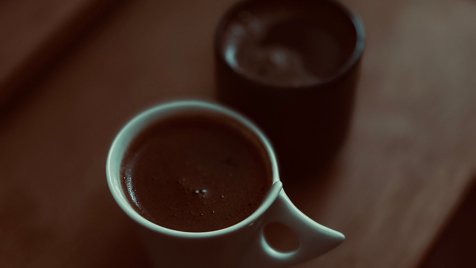 Two small coffee mugs on a wooden table