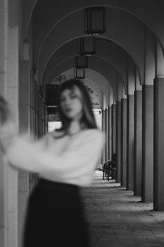 A black and white photo featuring a blurred woman against a colonnade, creating an urban and artistic effect.