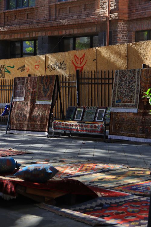 Free Colorful handmade rugs and textiles displayed in an outdoor market setting. Stock Photo