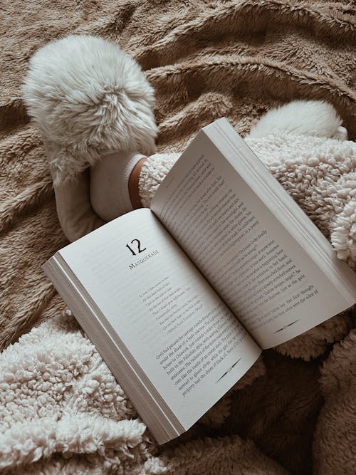 Free Person in Pajamas and Slippers Reading Book Stock Photo