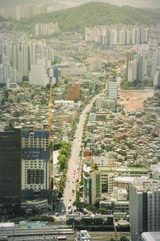 A stunning aerial view of a dense urban cityscape featuring high-rise buildings, streets, and surrounding landscapes.