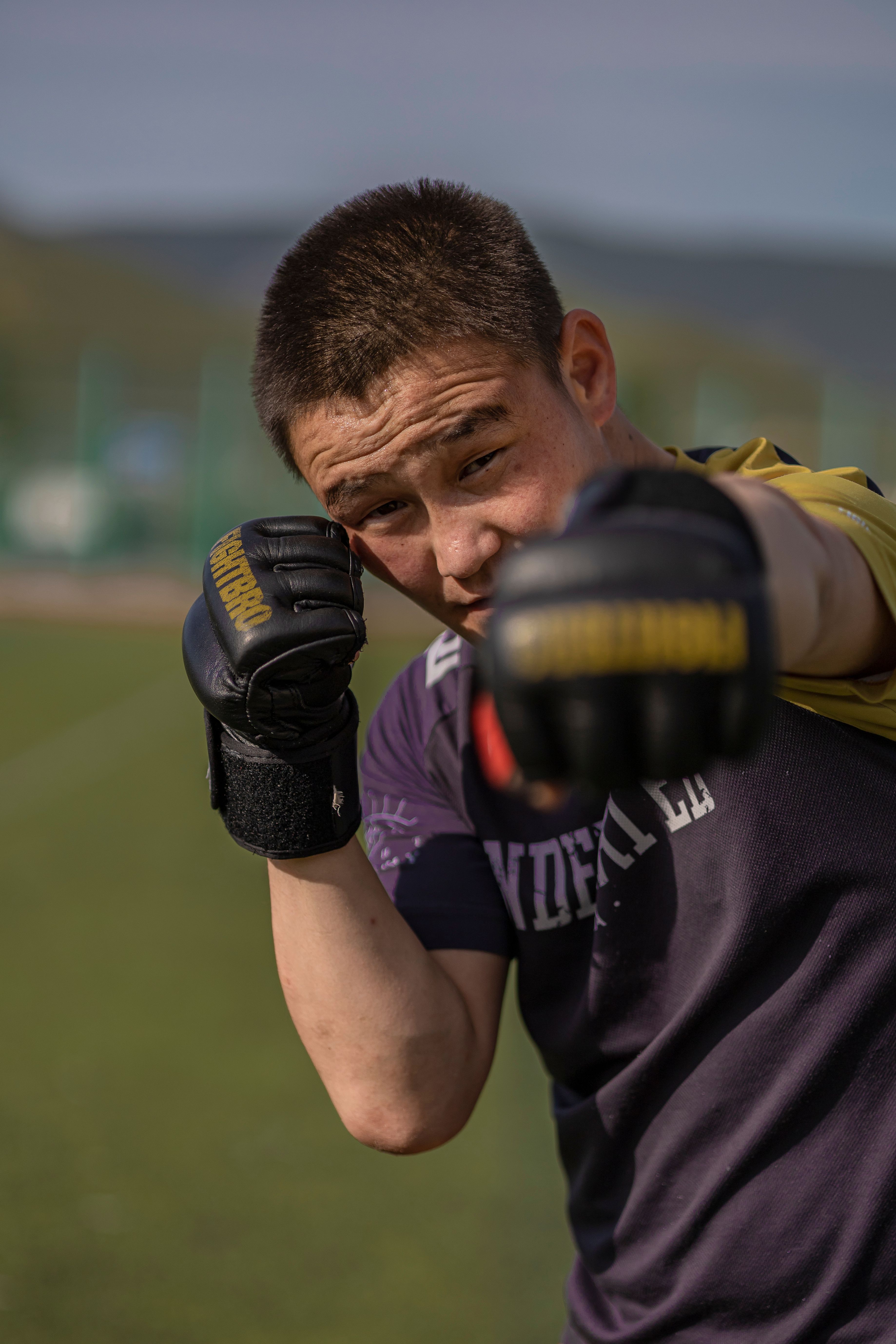 A young male boxer practicing his punches outdoors on a sunny day.