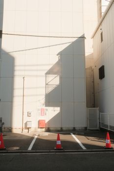 Sunlit urban parking lot with facades and striking shadows, creating a serene cityscape scene.