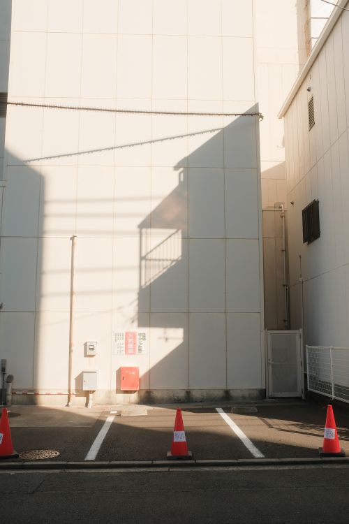 Free Sunlit urban parking lot with facades and striking shadows, creating a serene cityscape scene. Stock Photo