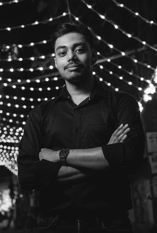 Free Stylish monochrome portrait of a confident man in a black shirt, set against festive lights. Stock Photo