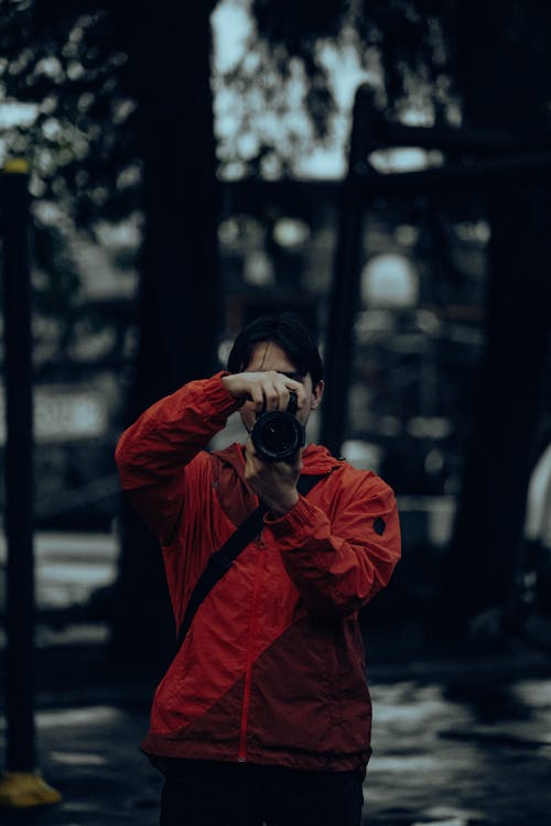 Man in Red Jacket Taking Photo with Camera