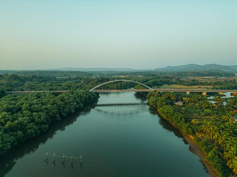 Scenic aerial view of a bridge over a river surrounded by lush greenery in Aldona, Goa, India.