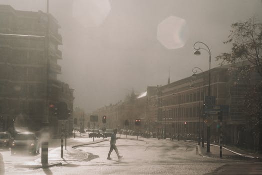 Dramatic urban street scene in the rain, featuring a lone pedestrian crossing.