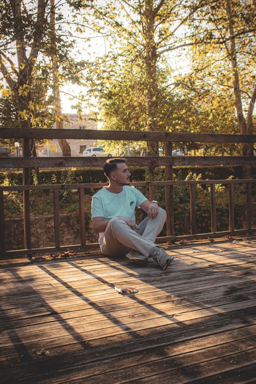 Man Sitting on Wooden Footbridge