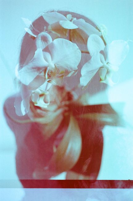 Creative double exposure image combining a woman's portrait with orchids in artistic composition.