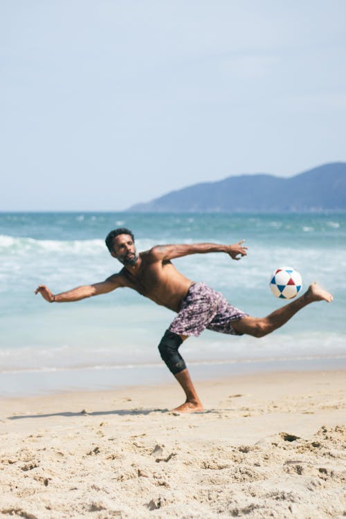 Man Kicking a Ball on the Beach 