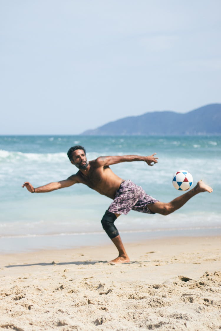 Man Kicking A Ball On The Beach 