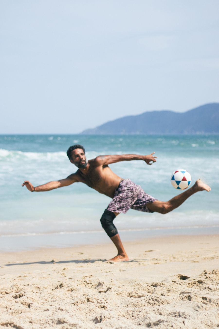 Jogador de futebol de praia em ação na areia