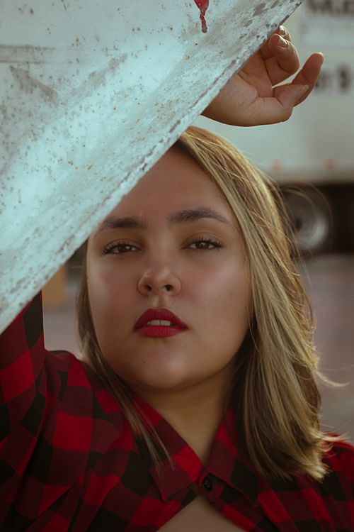 Free Close-up portrait of a woman posing with confidence in a red checkered dress outdoors. Stock Photo