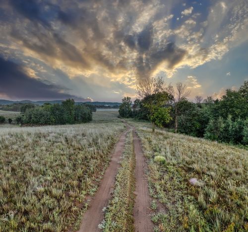 Free A dirt road stretches through a scenic countryside field under a dramatic sunset in West Newton, Minnesota. Stock Photo