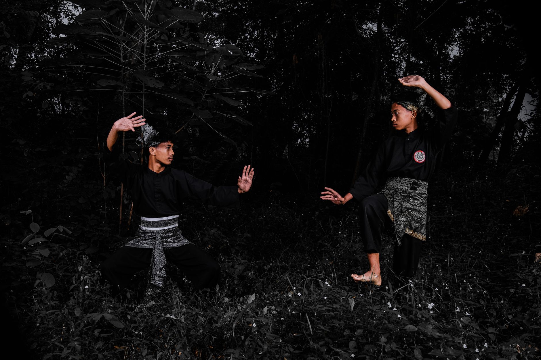 Two individuals practicing martial arts in a forested area.