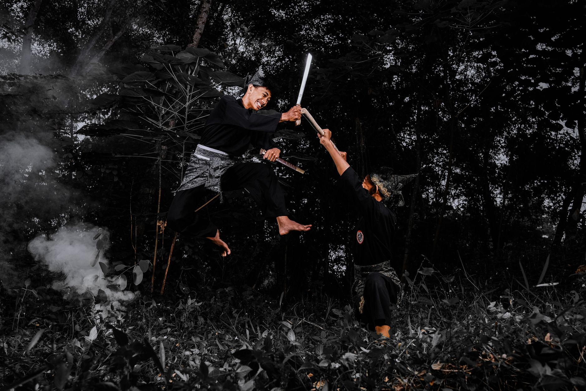 Two martial artists engaged in a high-flying sword fight in a dense forest.