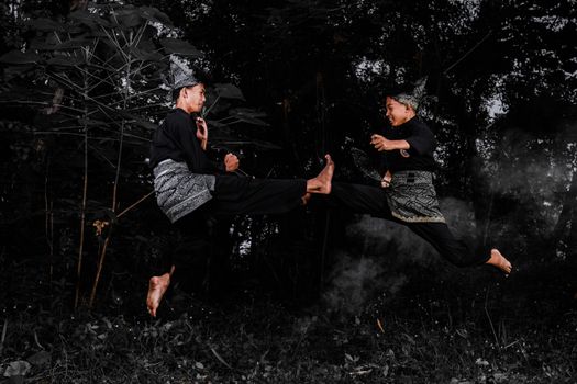 Two men practicing traditional martial arts outdoors, showcasing dynamic movement and cultural attire.