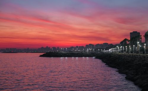 Free A stunning urban skyline with a waterfront view at sunset, featuring a dramatic sky. Stock Photo