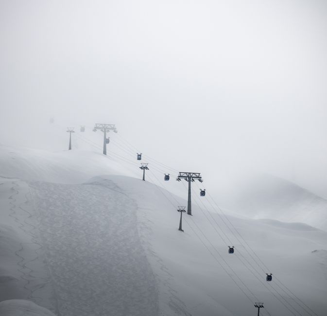 Snow-covered ski lift in Hintertux, Austria enveloped in misty winter atmosphere.