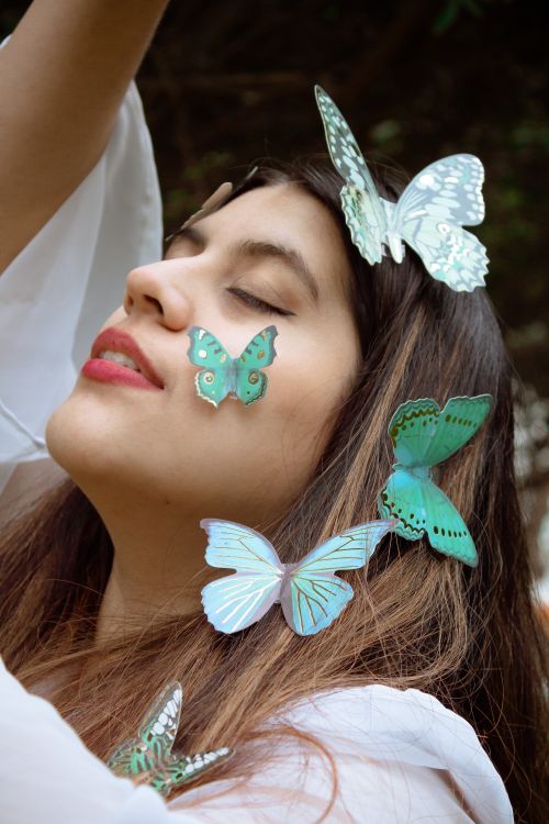 Free Close-up portrait of a peaceful woman adorned with vibrant butterflies, eyes closed, expressing tranquility. Stock Photo