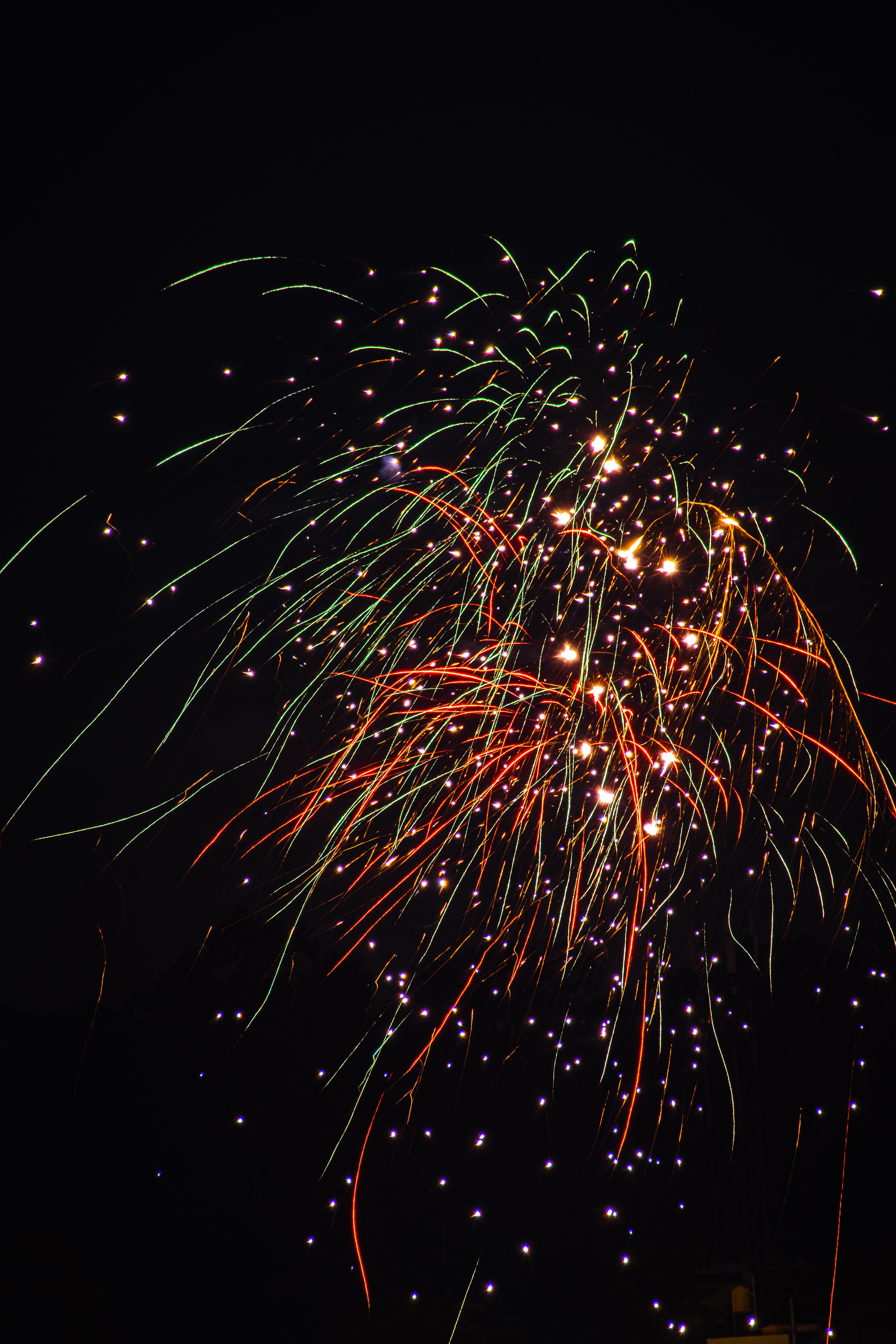 Fotomural Brillantes y coloridos fuegos artificiales estallando contra un oscuro cielo nocturno, creando una atmósfera festiva.