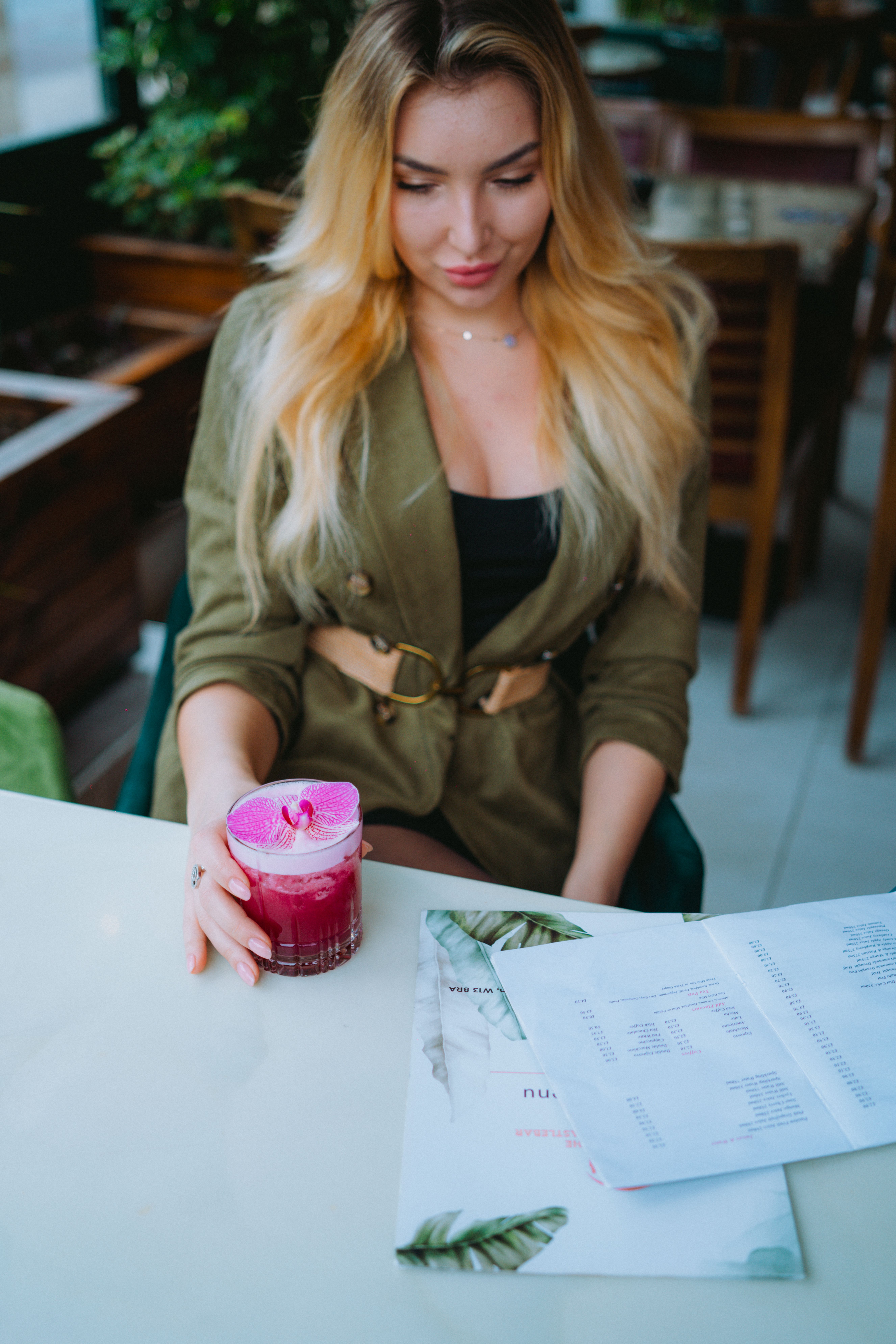 Blonde woman enjoying a pink cocktail in a stylish restaurant setting.