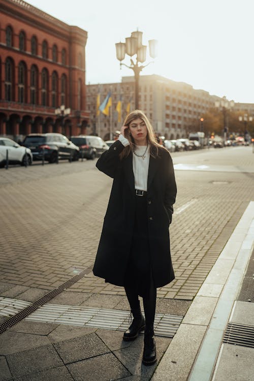 Young Woman in a Coat Standing on the Street in City 