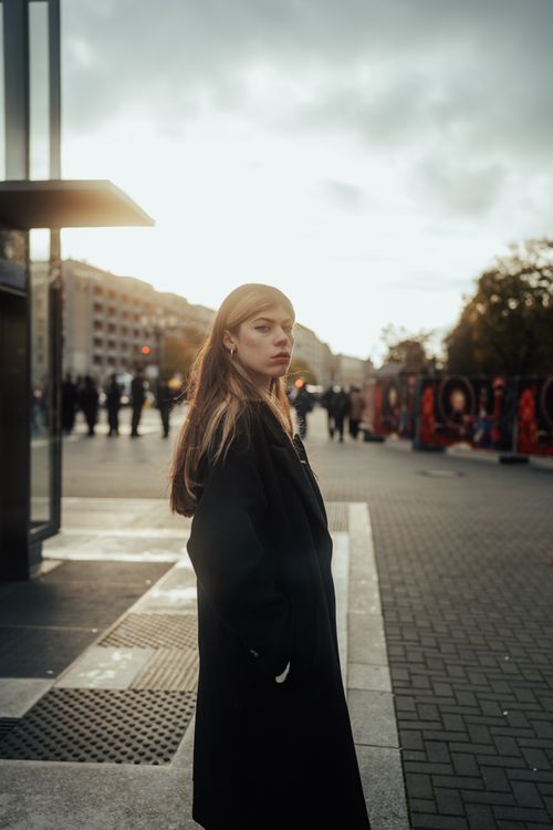 Free Stylish woman in a coat walking through a city street at sunset. Urban fashion mood. Stock Photo
