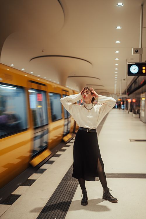 Free Woman in stylish attire posing in an underground station with a moving train. Stock Photo