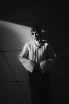 Elegant woman in knitwear poses in dramatic black and white lighting.