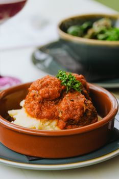 Delicious meatballs with tomato sauce atop creamy mashed potatoes in a rustic setting.