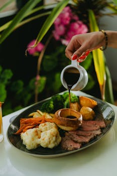 A beautifully arranged roast dinner with vegetables, poured with gravy for a gourmet touch.