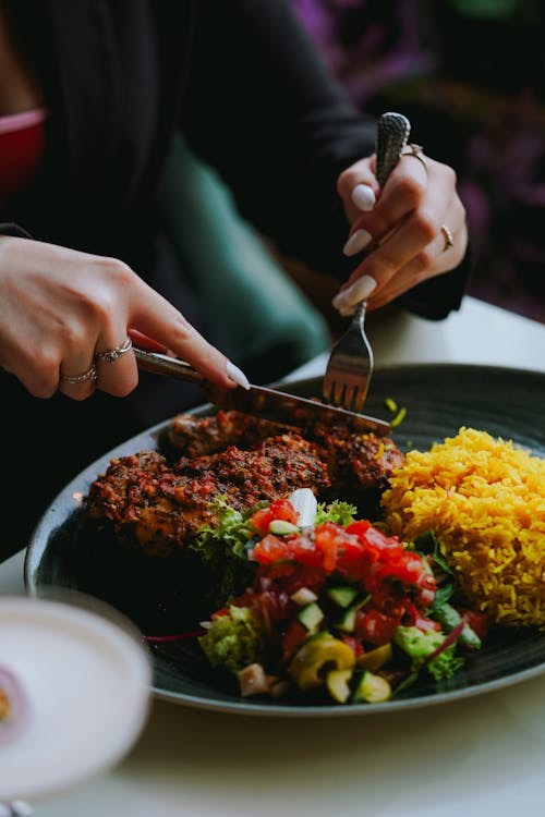 Close-up of Woman Cutting Food on the Plate 